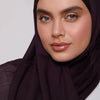 Gros plan d'une femme portant un foulard modal de couleur prune foncé.