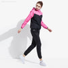 Une femme portant une combinaison de fitness noire et rose, debout et posant.