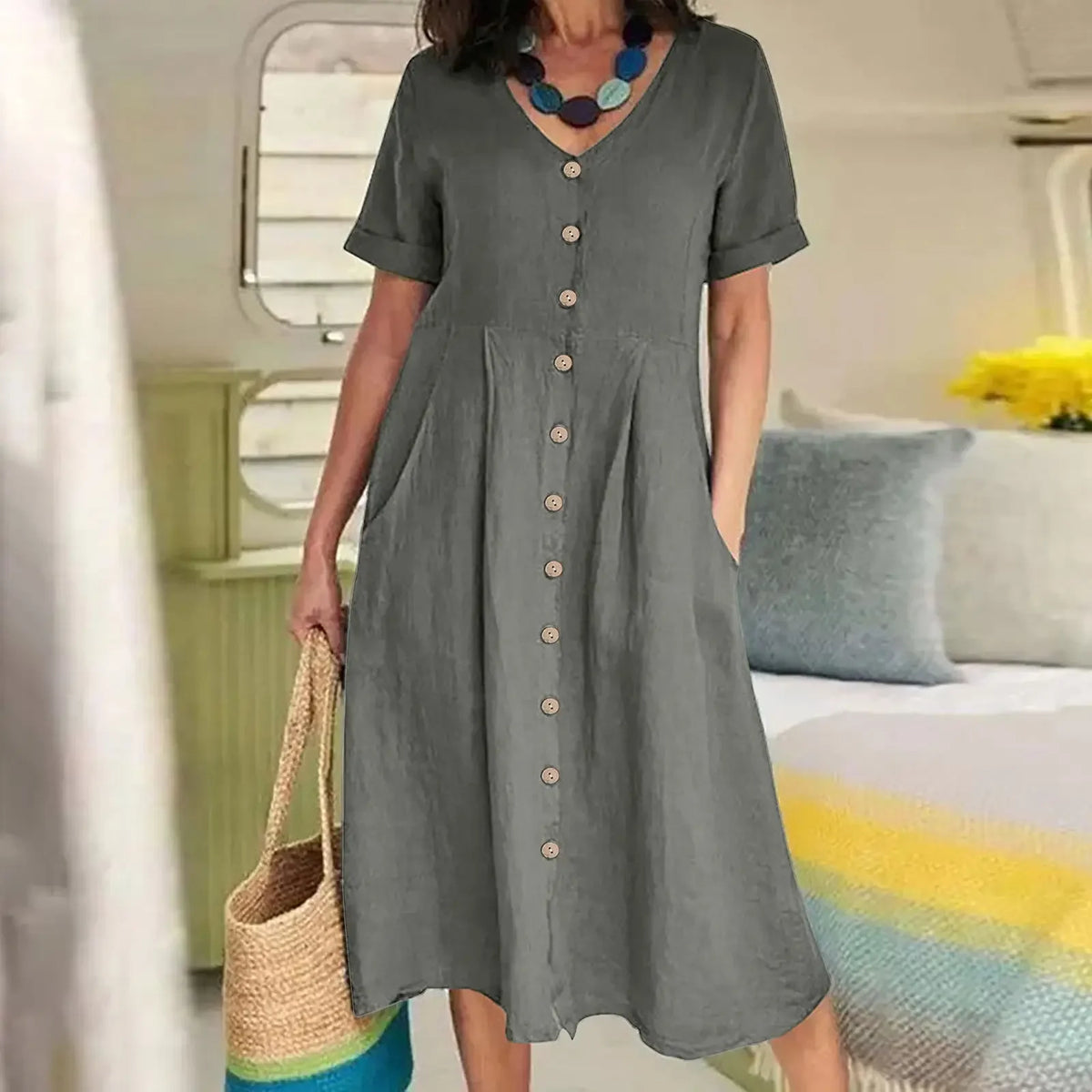 Eine Frau modelliert ein elegantes graues Baumwoll- und Hanf-V-Ausschnittkleid in sanftem, natürlichem Licht.