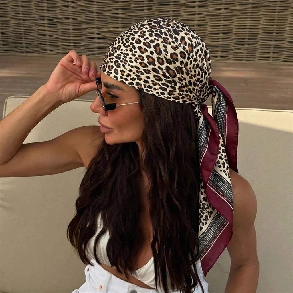 A woman wearing an elegant silk dot print scarf for hair and neck, with long dark hair.
