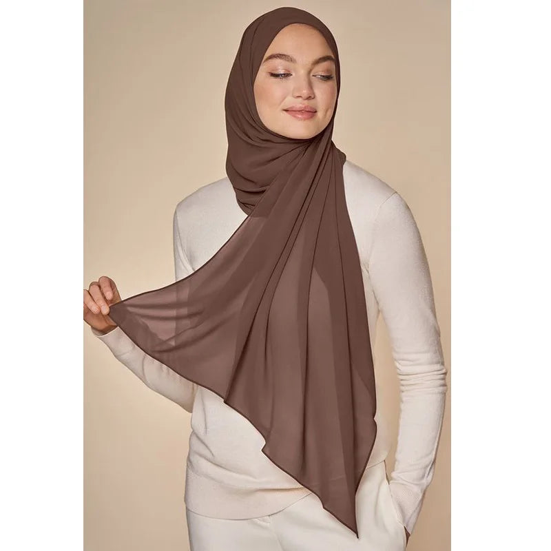 Eine Frau trägt einen einfarbigen braunen Chiffon-Hijab und ein helles Oberteil.