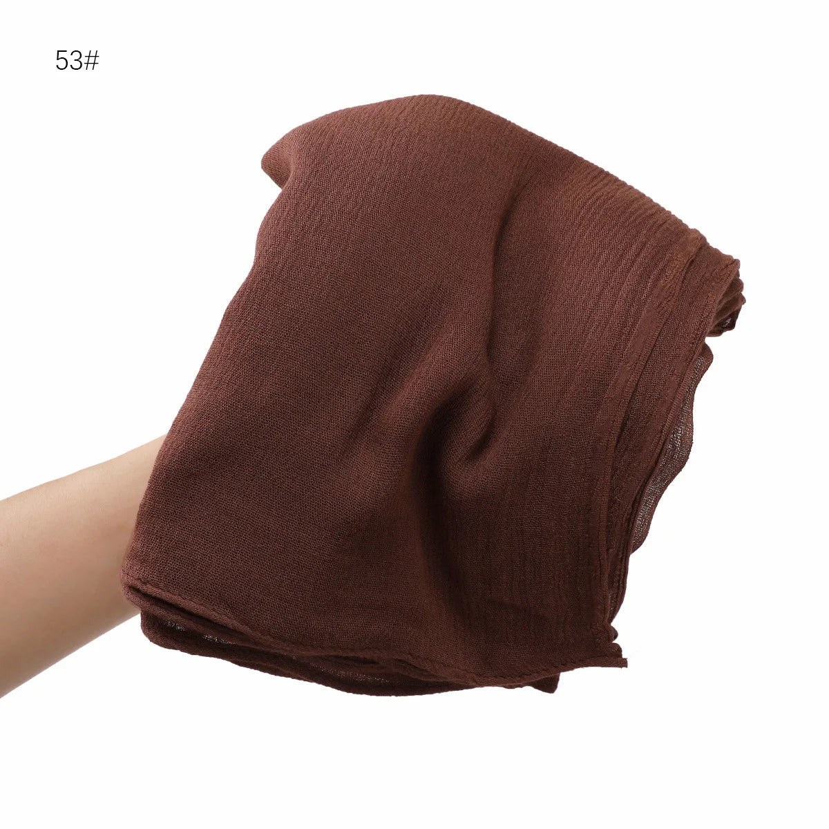 Écharpe châle en rayon marron foncé et froissé drapée sur une main.
