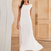 A woman models a white flowing modest abaya dress in a light beige room.