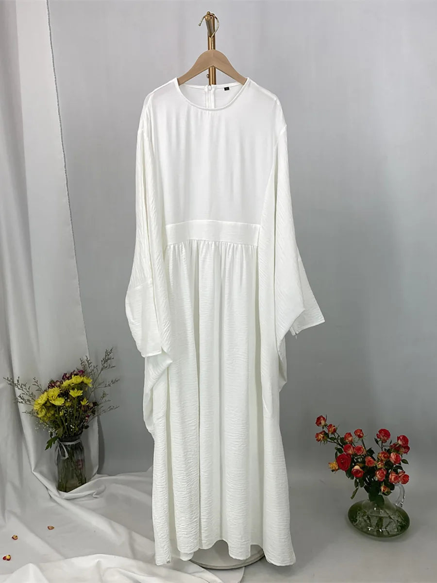 Elegane weiße Batwing-Abaya für Damen, an einem Kleiderbügel vor grauem Hintergrund.