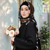 Une femme portant une tenue noire et un hijab en viscose à imprimé léopard, tenant un bouquet de fleurs.