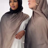 Zwei Frauen tragen passende taupe- und schwarze Hijabs und posieren nebeneinander.