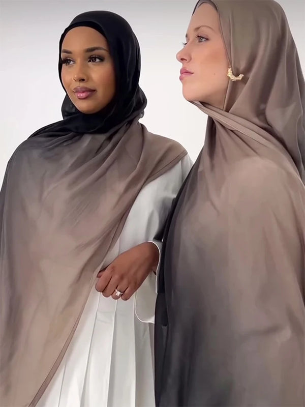 Two women wearing matching taupe and black hijabs, posing side by side.