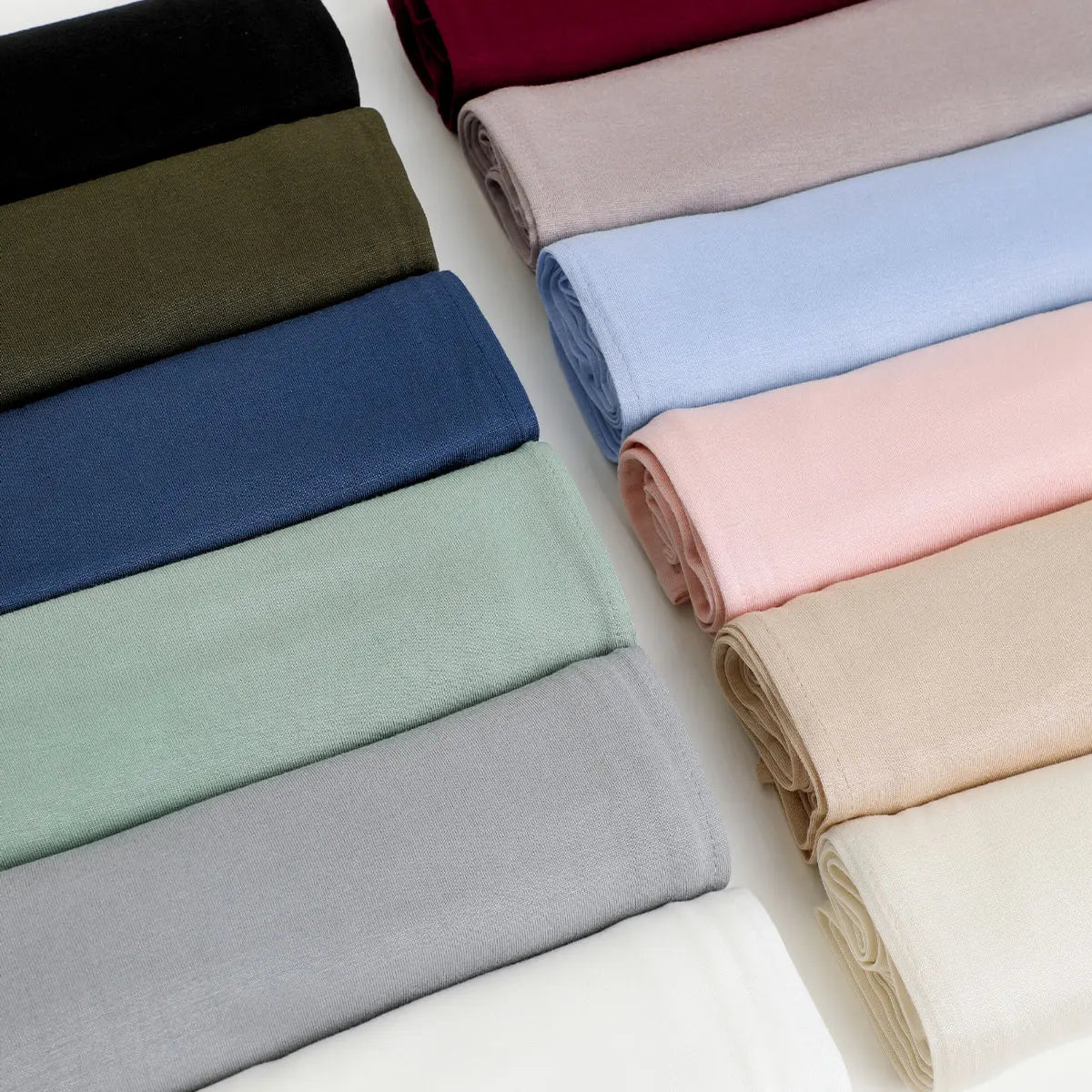 Stapel eleganter Chiffon-Schals oder Überwürfe in verschiedenen Farben wie Schwarz, Olivgrün, Blau, Pink und Beige