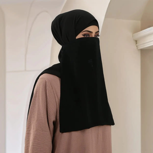 A woman wearing a black breathable mesh full face hijab and neck scarf with a beige top.