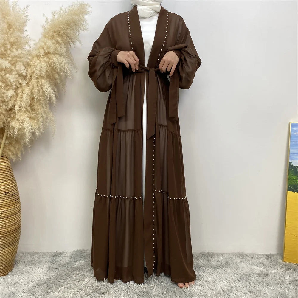 Cardigan abaya marrón elegante de manga larga y frente atado, usado sobre una prenda blanca.