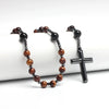 Collier avec des perles de œil de tigre et d'hématite, se terminant par un pendentif croix noire.