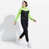 Une femme portant une combinaison de fitness noire et vert lime, debout sur un fond blanc.