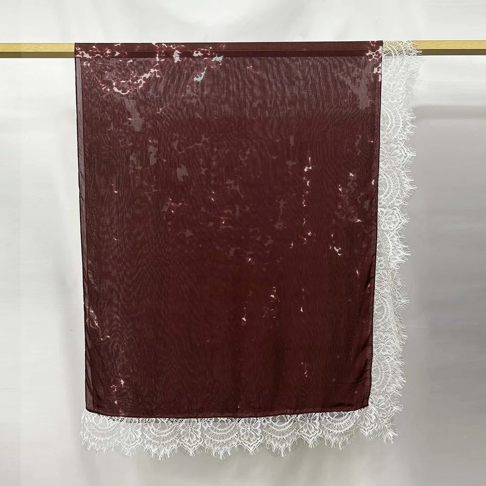 Hijab de encaje color granate oscuro, estampado doble cara, colgado en una varilla de madera.