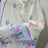 Primer plano de un vestido kaftan maxi estampado floral en crema y morado, mostrando detalles elegantes de la tela.
