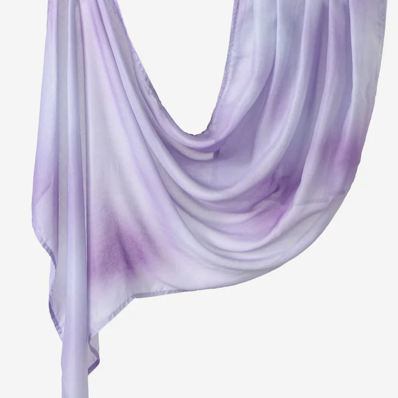 A purple and white printed linen hijab scarf draped elegantly.