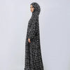 Una mujer vistiendo una abaya de lino floral negra con capucha y turbante, vista de frente.