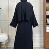 A full-length black abaya and kaftan set worn by a model, photographed indoors.