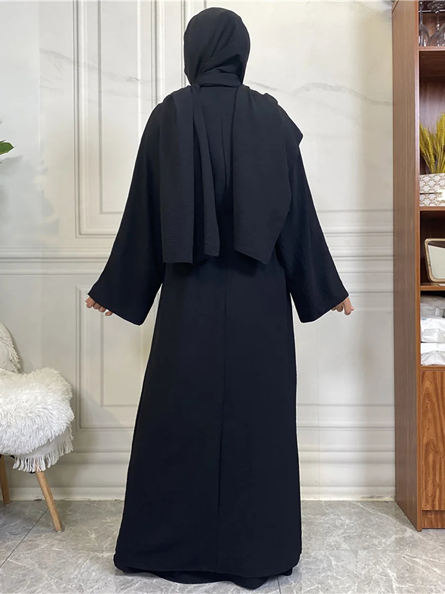 A full-length black abaya and kaftan set worn by a model, photographed indoors.