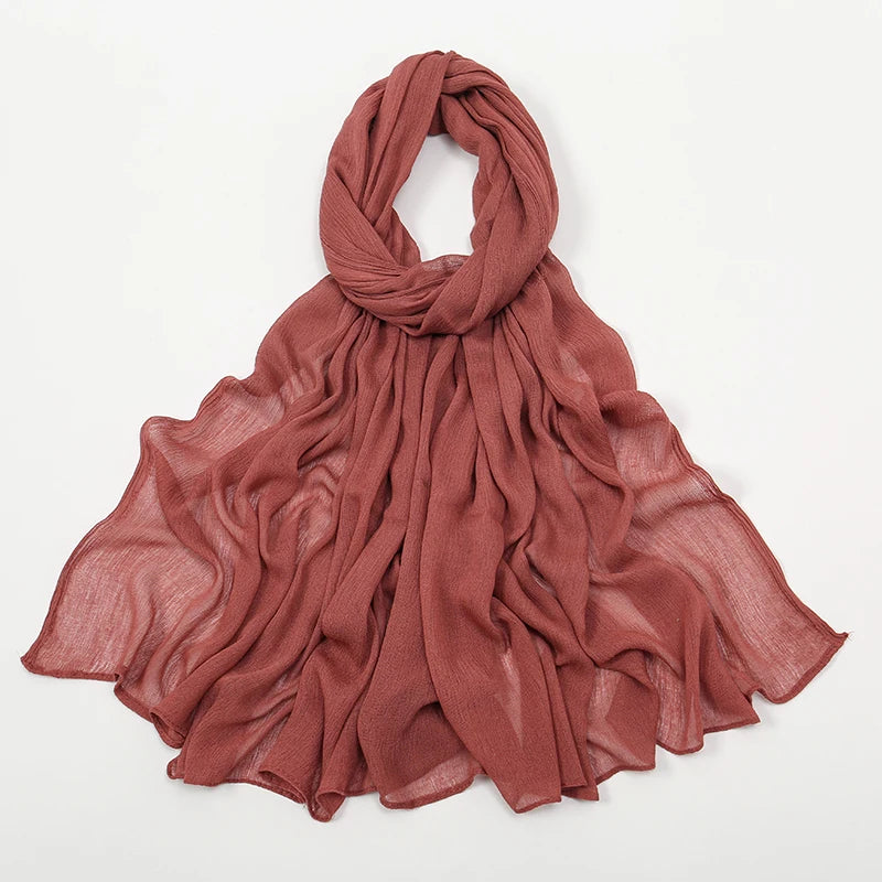 Étoffe crinkle couleur rouille, foulard en rayon drapé autour du cou et sur les épaules.