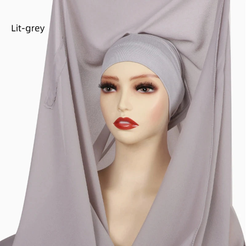 Model trägt einen hellgrauen Instant-Chiffon-Hijab mit einer Kappe, drapiert über Kopf und Schultern.
