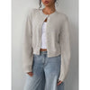 Une femme portant un pull tricoté beige clair sur un haut blanc et un jean bleu.