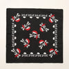 Tissu noir avec un motif répétitif de crânes et de tibias en rouge et blanc.