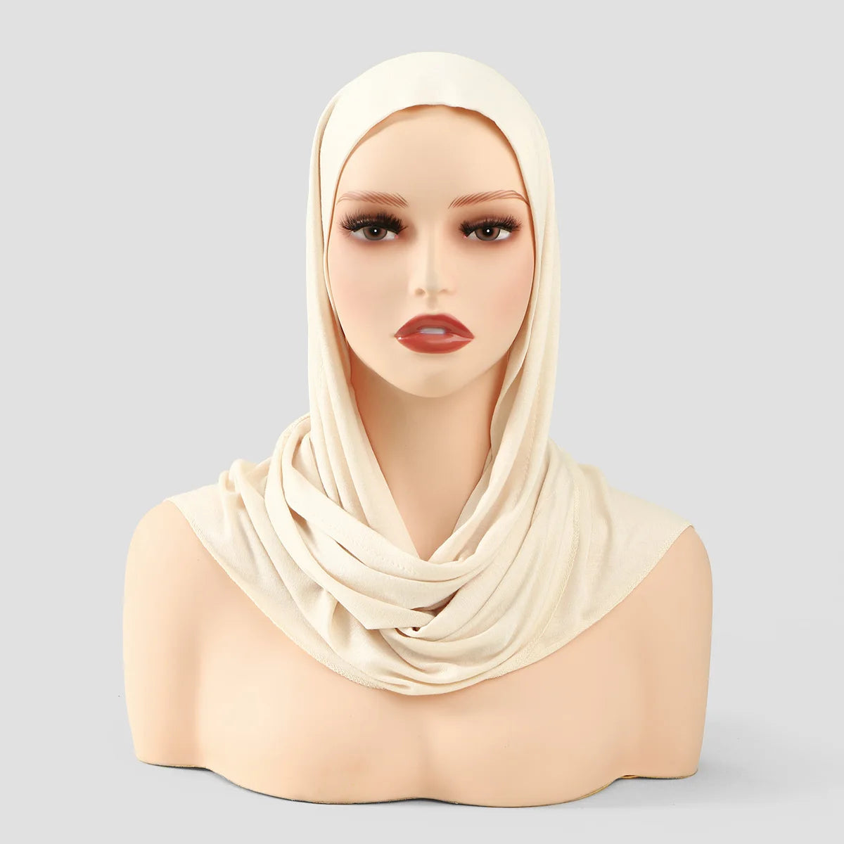 Model wearing a beige instant ready-to-wear jersey hijab scarf around her neck and head.