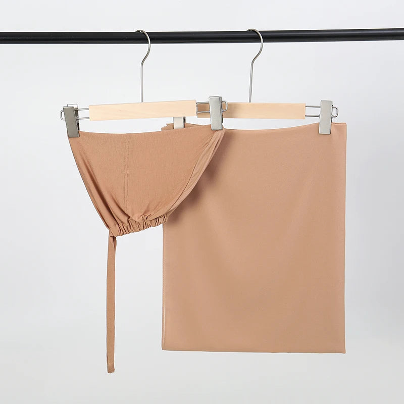 Beige Chiffon-Hijab und Untercap-Set an einem schwarzen Stab hängend.