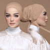 Una mujer vistiendo un elegante turbante de hijab modal beige y una blusa blanca.