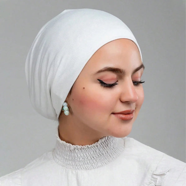 A woman wearing a white stretch jersey inner hijab cap and matching top.