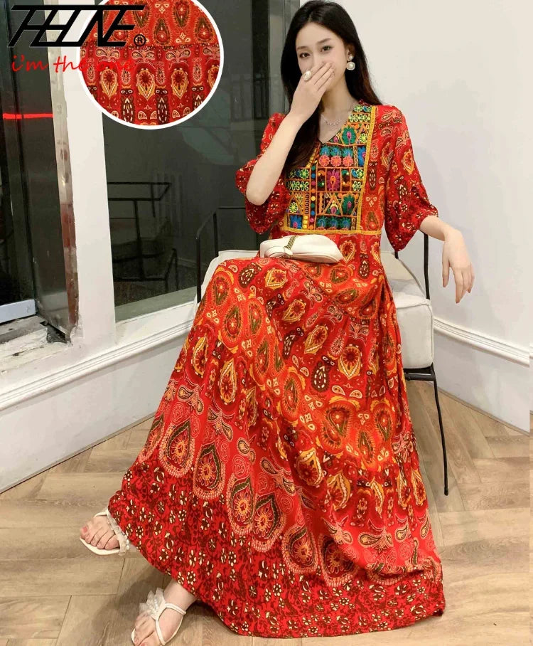 Eine Frau modelliert ein leuchtend rotes, bohemiss-besticktes Maxi-Kleid mit komplexen Mustern.