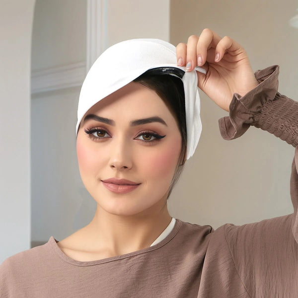 A woman is adjusting a white anti-slip inner hijab cap on her head.