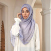 Eine Frau trägt einen helllila Aquarell-Digitaldruck-Hijab und ein weißes Oberteil in einem Innenraum.