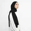 Eine Frau trägt einen schwarzen Instant-Hijab-Schal über einem weißen Oberteil.