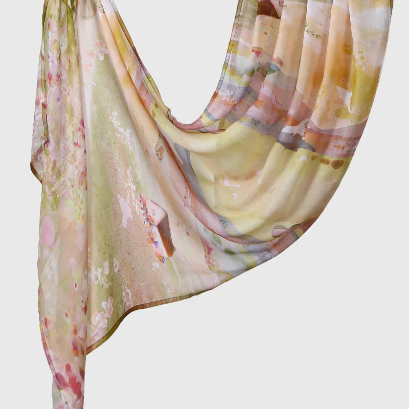 A flowing, sheer linen hijab scarf with an elegant watercolor print featuring soft peach, pink, and pale green tones.