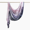 Elegant printed linen hijab scarf draped over a hanger, featuring shades of pink, purple, and gray.