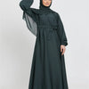 Eine Frau in einem dunkelgrünen marokkanischen Kaftan-Abaya mit Hijab, von vorne.