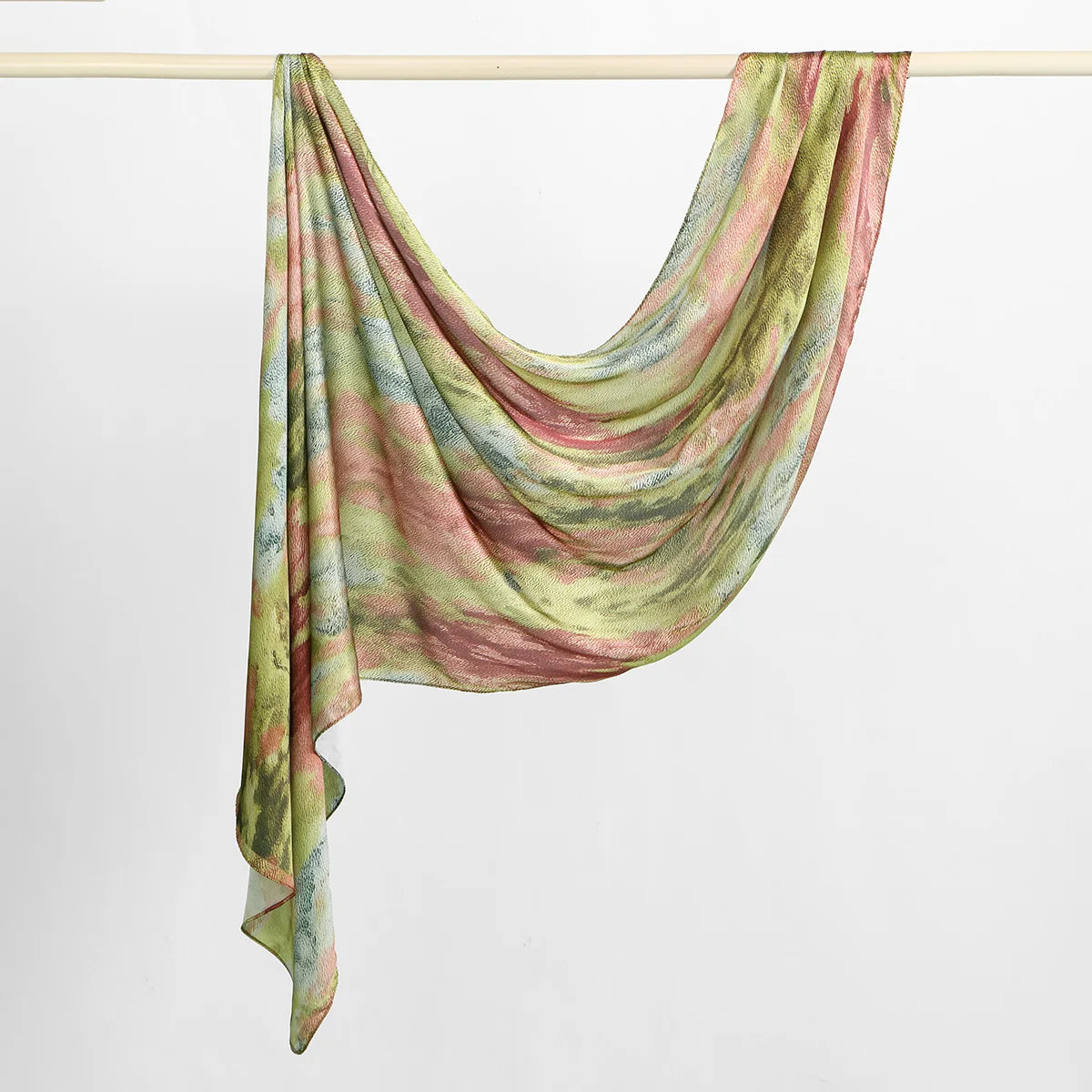 Écharpe hijab en satin de soie imprimée, rose, vert et beige, drapée sur un cintre.