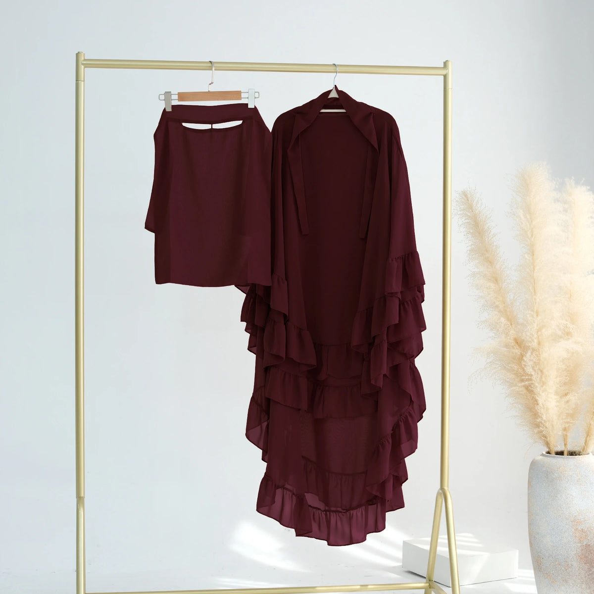 A maroon ruffled 2-layer chiffon hijab displayed on a gold hanger against a white background.