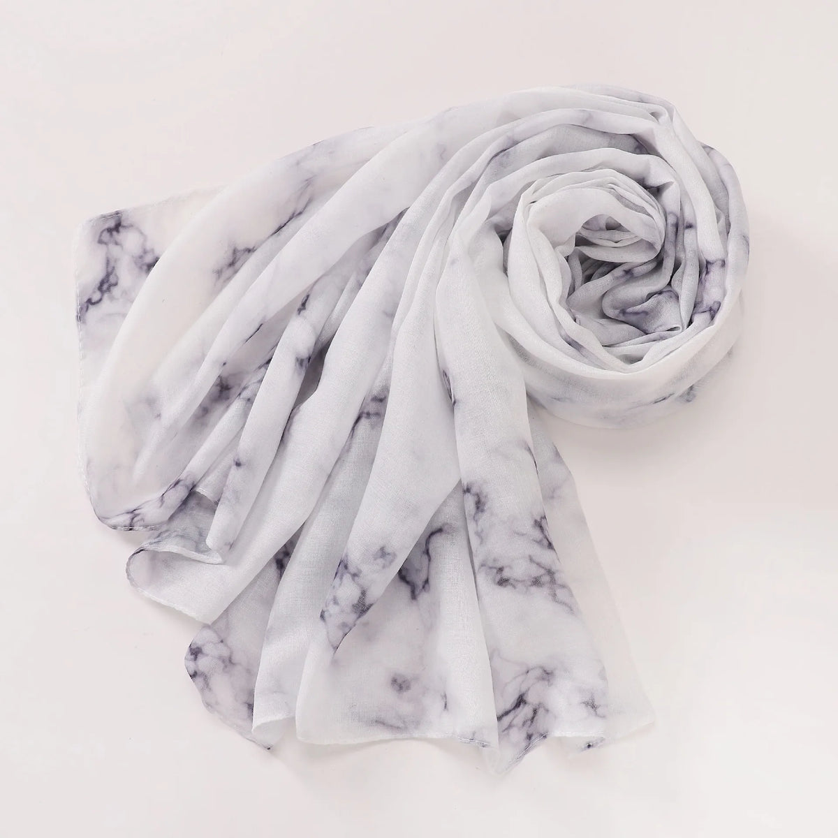 Pañuelo o hijab de tela marmolada blanca y gris, doblado en espiral.