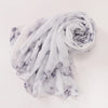 Pañuelo de tela marmolada blanca y gris enrollado en espiral.