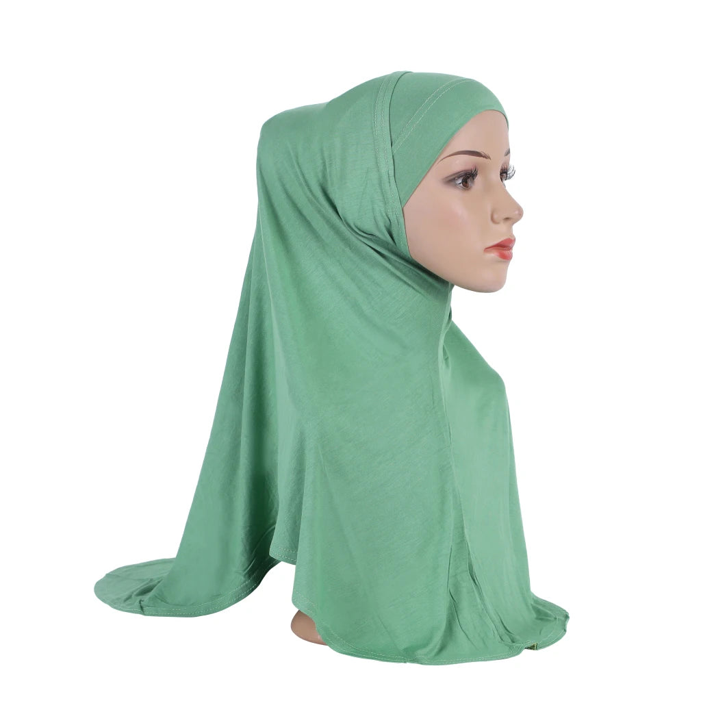 Una modelo vistiendo un pañuelo de algodón modal verde salvia sobre su cabeza y hombros.