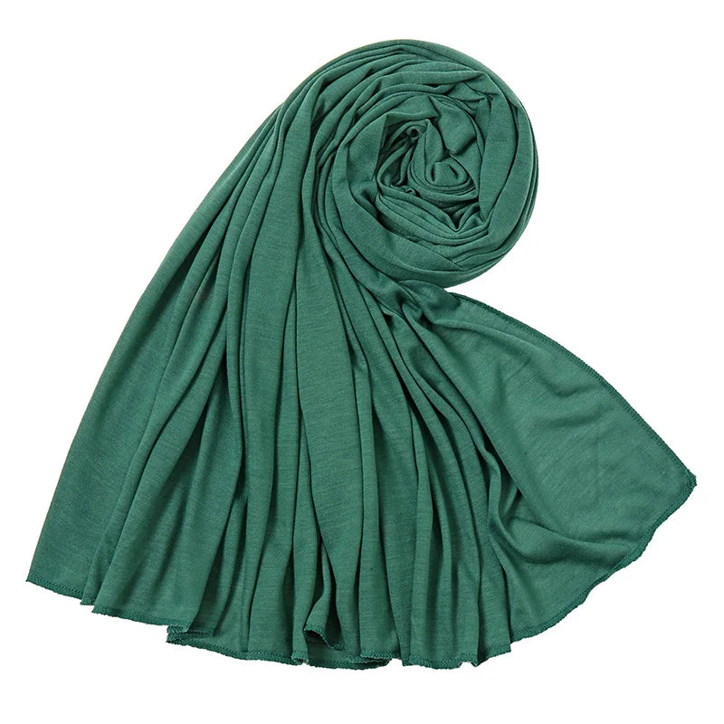 Foulard hijab en jersey de coton vert émeraude roulé en spirale.