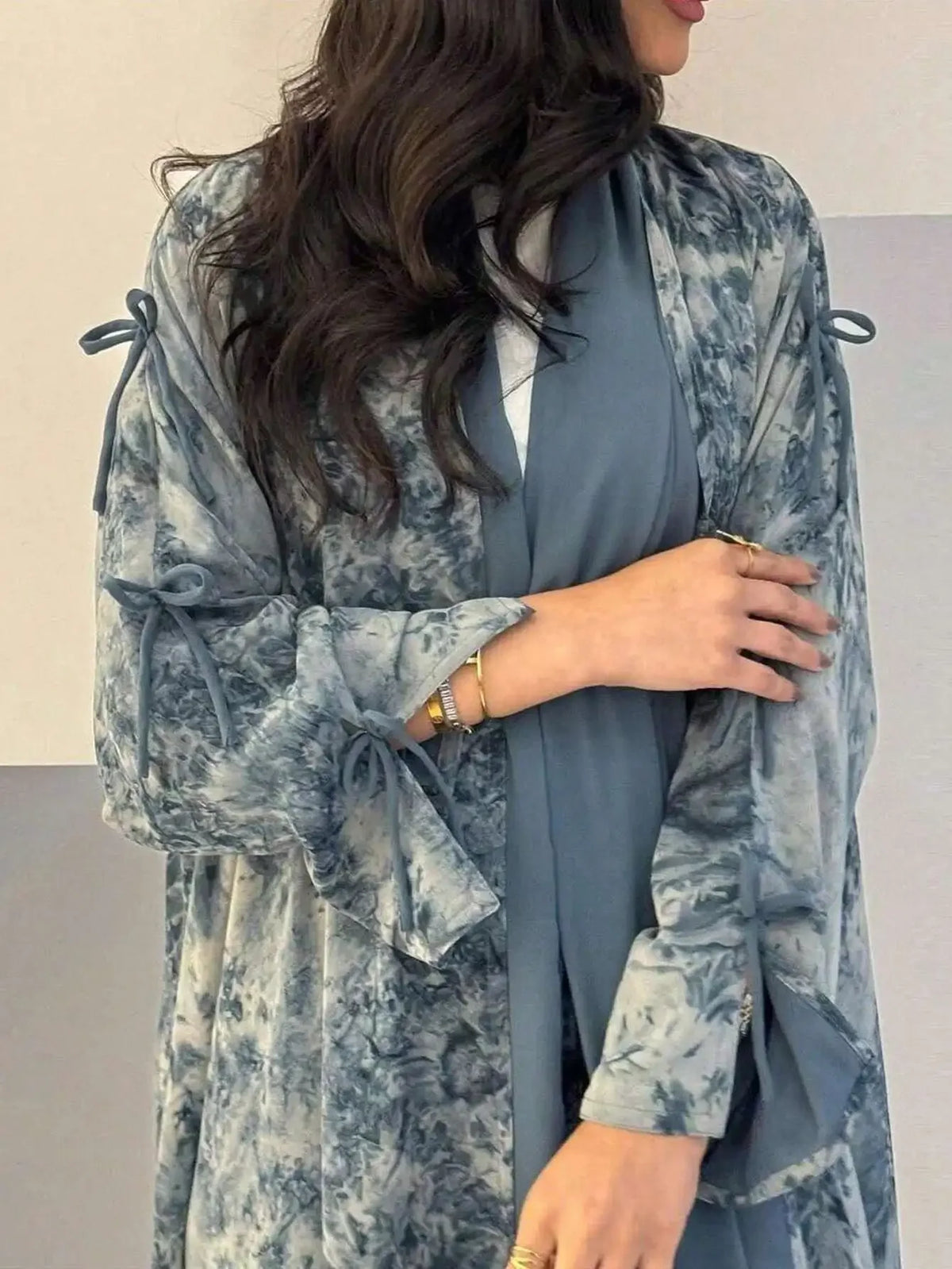 Eine Frau trägt einen fließenden Tie-Dye Abaya Kaftan in blauen und grauen Tönen.