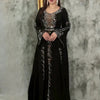 Eine Frau trägt ein elegantes schwarzes Abaya-Kleid mit durchscheinenden Rüschenärmeln und silbernen Verzierungen.