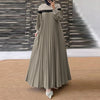 Une femme portant une caftan abaya longue, fluide, vert olive avec plis verticaux et bordure noire.