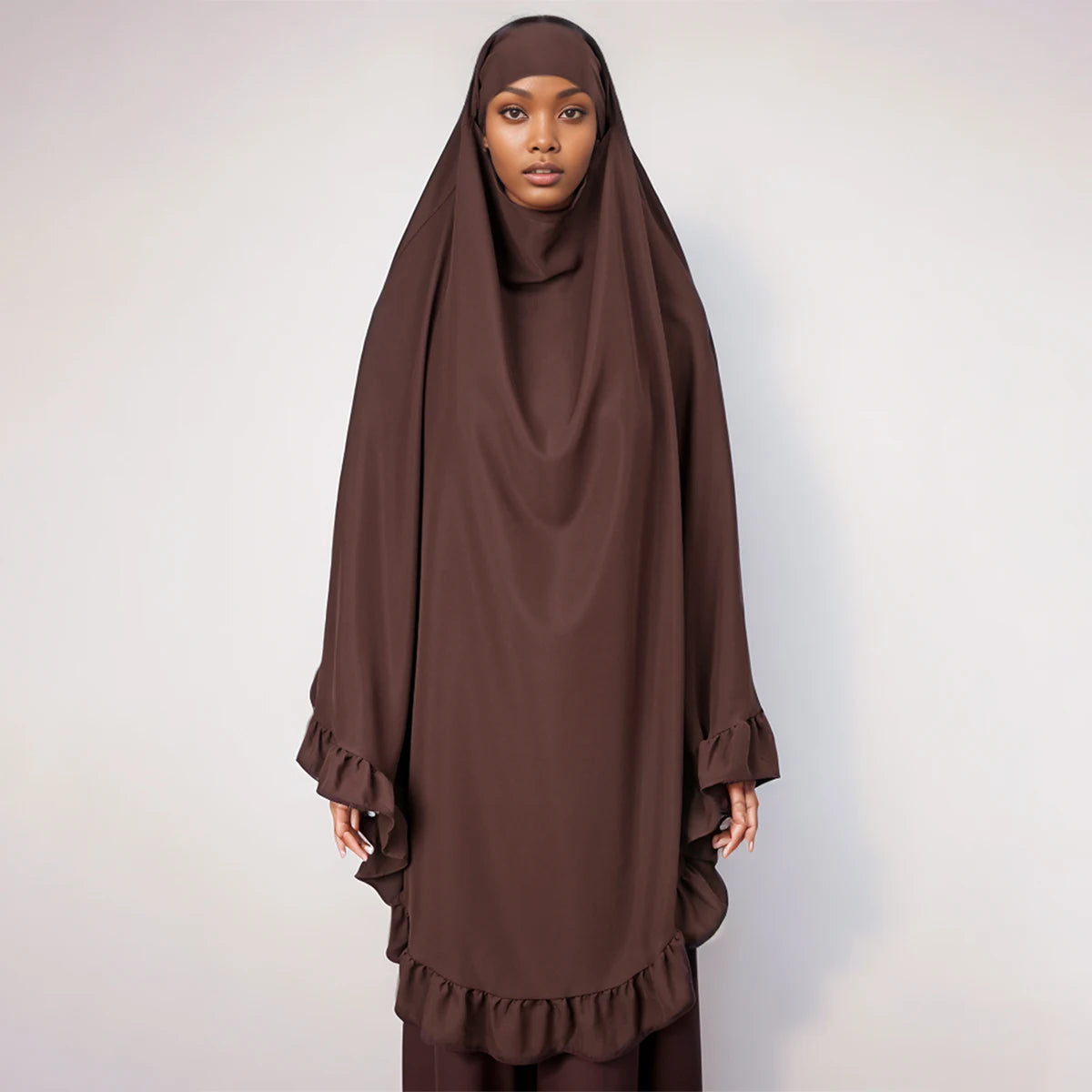 Eine Frau trägt einen einfarbigen braunen Hijab mit gerafften Rändern.