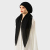 Une femme portant un foulard carré noir et un châle assorti avec un haut blanc.