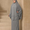 Eine Frau in einem grauen mehrlagigen Spitzen-Khimar-Abaya-Set vor neutralem Hintergrund.