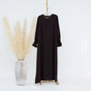 Vestido abaya largo y oscuro marrón, de corte holgado, colgado en percha contra fondo blanco.